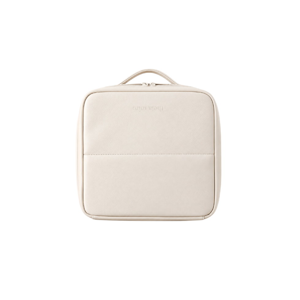 A cream-colored faux leather travel pouch with a top handle, shown from a front-facing perspective on a solid white background.