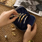 Navy blue jewelry case with gold and silver necklaces on a textured surface