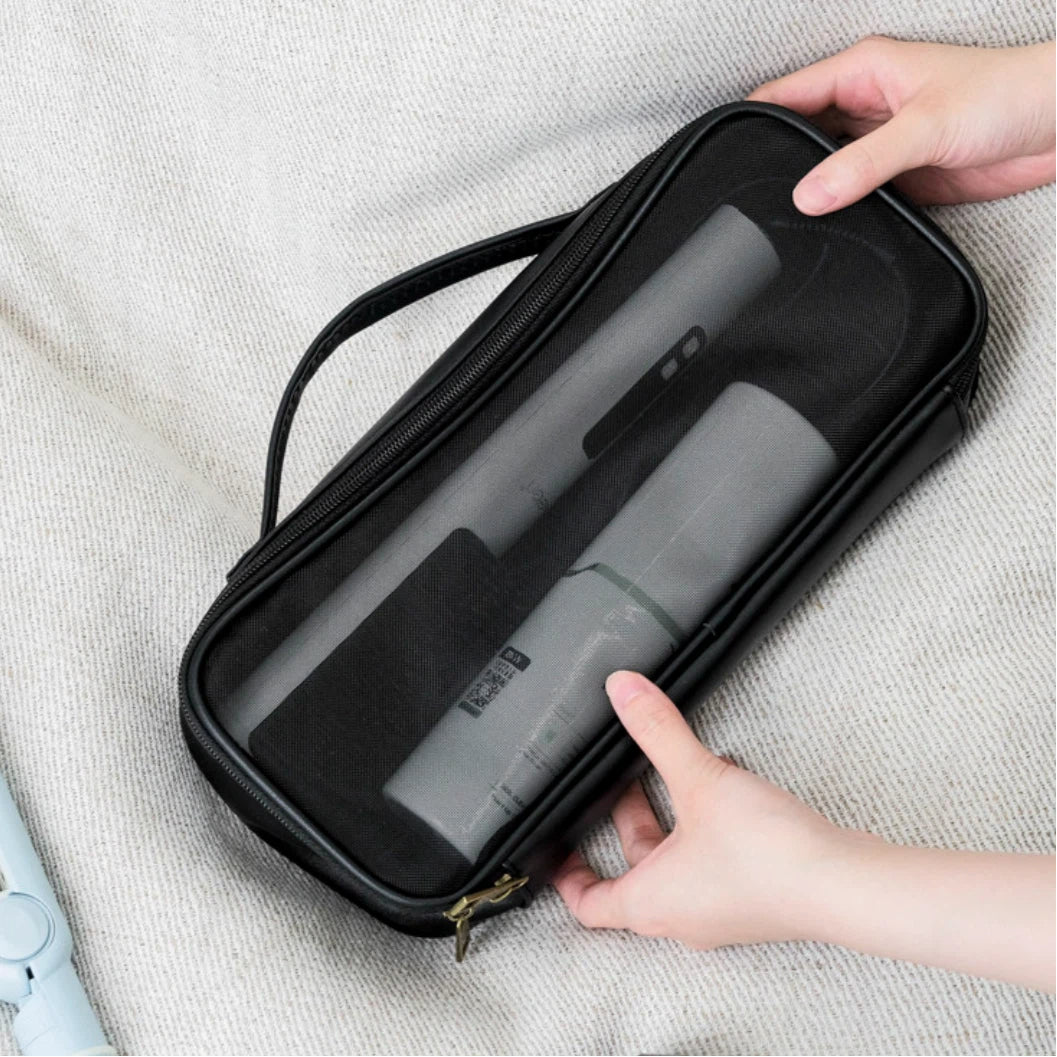 Black hairdryer case with a gray hair straightener inside, held by hands on a light gray fabric background.
