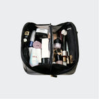 Open makeup bag with various cosmetic products on a light gray background