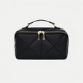 Black quilted makeup bag with gold zipper on a light gray background