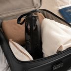 Open suitcase with clothes and a black makeup bag inside