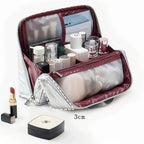An open silver cosmetic bag with burgundy lining, shown filled with makeup items and a translucent pouch. A small lipstick and compact are placed beside it, with a '3cm' size marker on a clean white background.