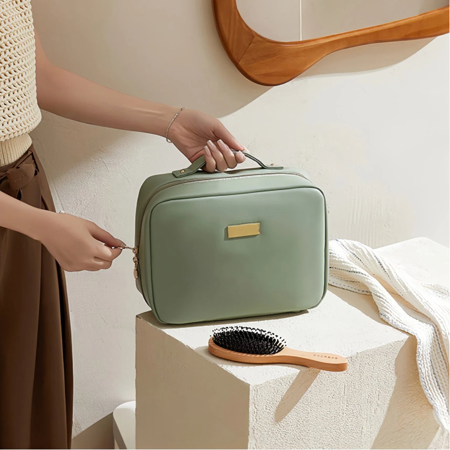Person holding a green travel case with a brush on a white surface