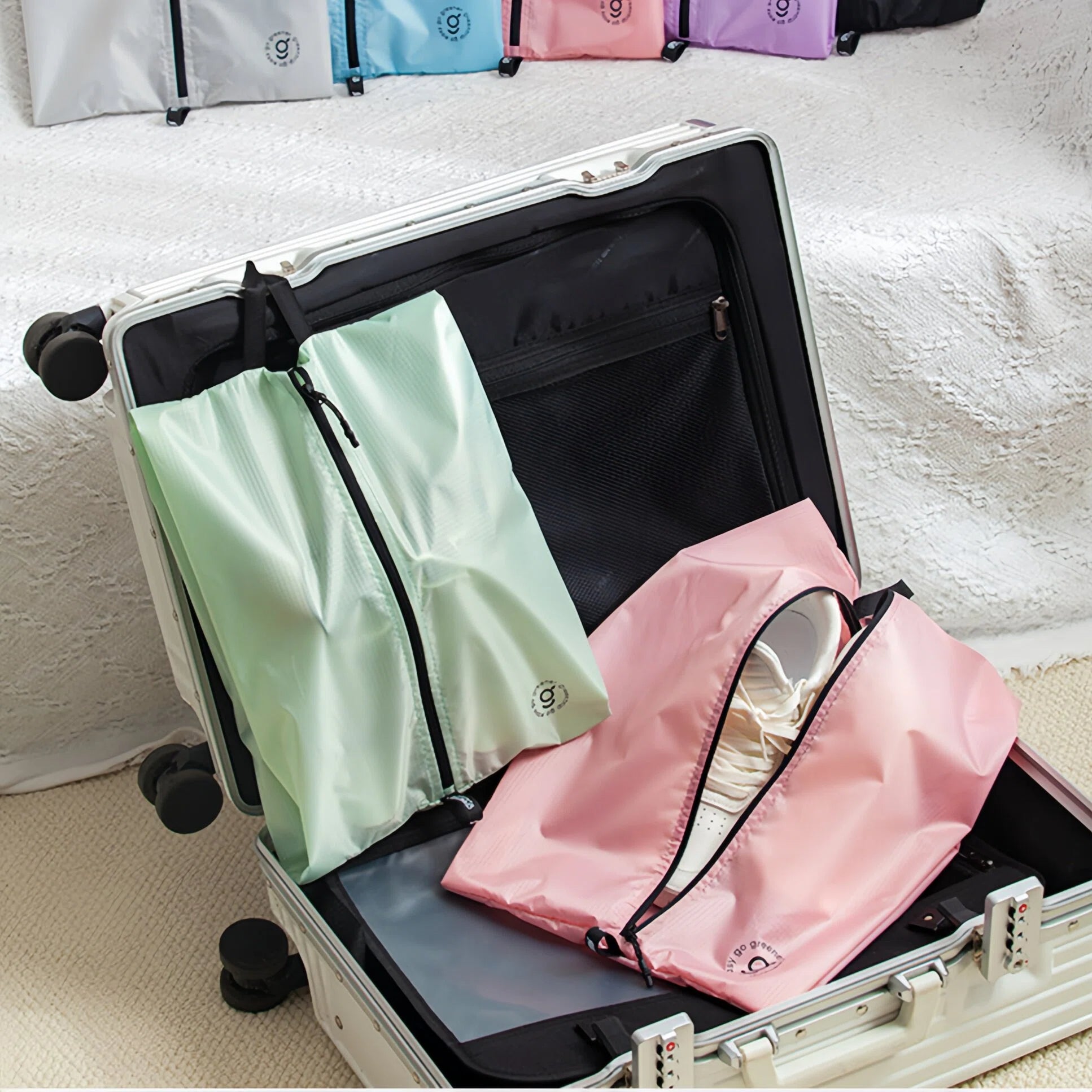 Suitcase with green and pink shoe bags inside, on a light-colored surface.