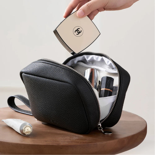 Black makeup bag opened with cosmetics products inside