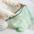 Person holding a light green travel bag with a brand logo on a white textured surface