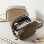 Olive grey makeup bag opened with cosmtics inside, and a beige makeup bag at the back