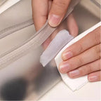 Person wiping the stain on the bag with a tissue