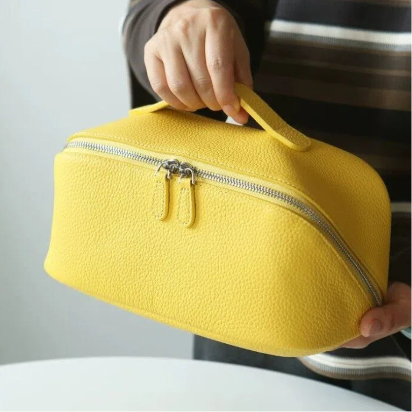 Yellow makeup bag held by a person with a neutral background