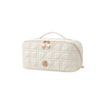 A cream quilted cosmetic bag with gold-tone hardware, featuring a top handle, zippered closure, and a decorative logo on the front.