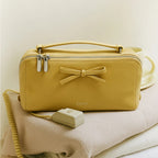 Yellow makeup bag with a bow and matching cable on a light background