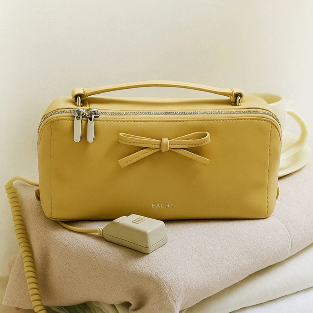 Yellow makeup bag with a bow and matching cable on a light background