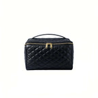 Black quilted cosmetic bag with gold zippers on a white background