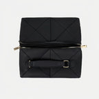 Folded black quilted makeup bag with gold zipper on a light gray background