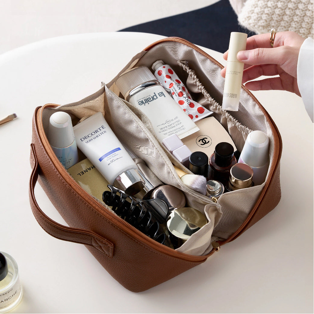 Open brown cosmetic bag with various skincare products on a light background