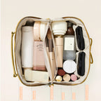 Open cosmetic bag with various skincare and makeup products on a light beige background