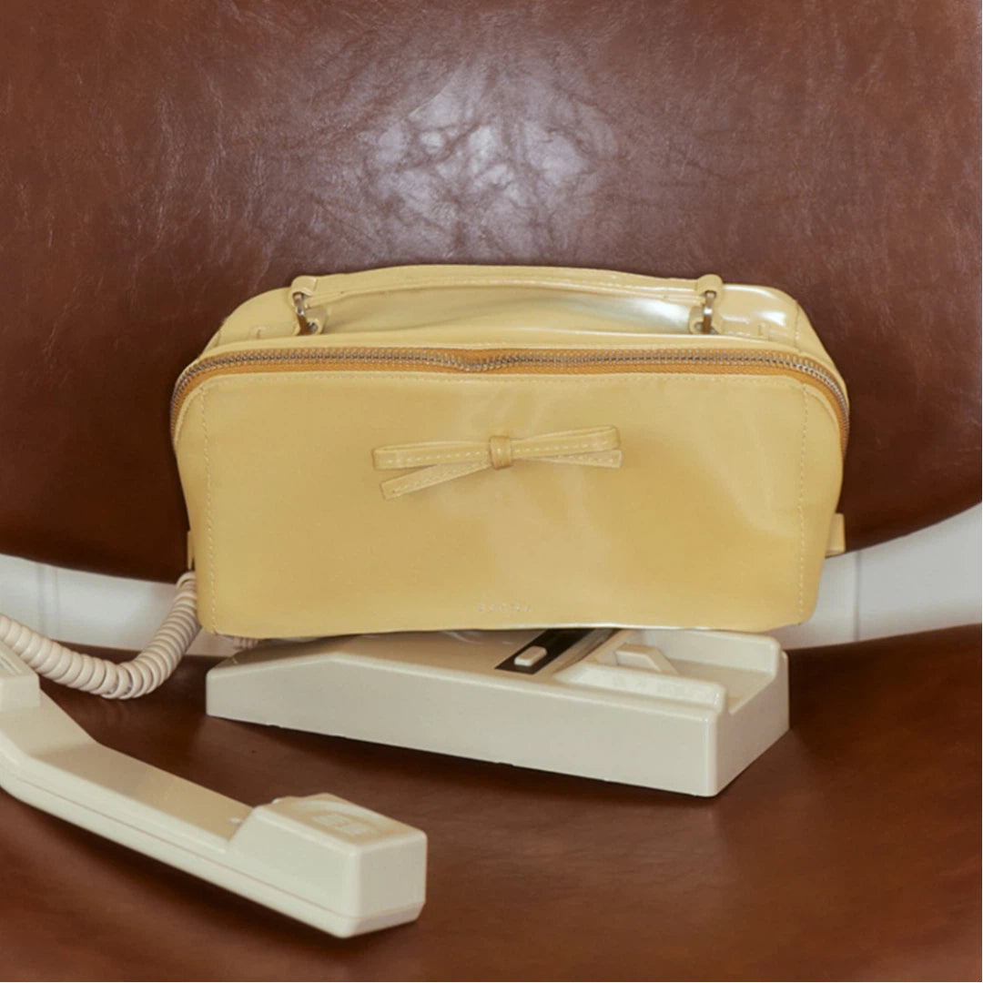 Yellow makeup bag on a vintage-style phone with a brown leather background
