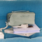 Light green makeup bag with a bow on a blue textured surface