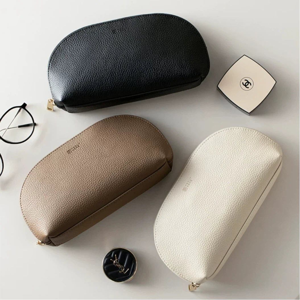 Three leather cases in black, beige, and white on a light surface.
