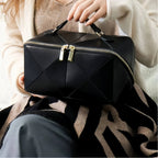 Person holding a black quilted makeup bag with a gold zipper.