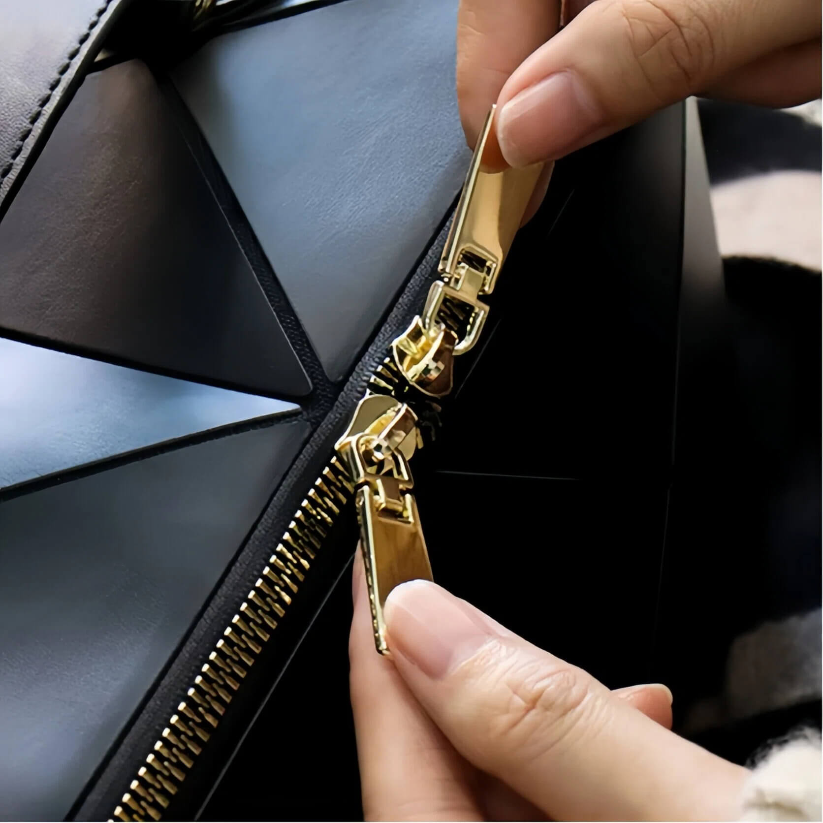 Close-up of hands zipping a black makeup bag with gold zipper.
