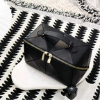 Black geometric makeup bag with gold zipper on a black and white patterned surface
