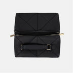 Folded black geometric-patterned makeup bag with gold zipper on a light gray background