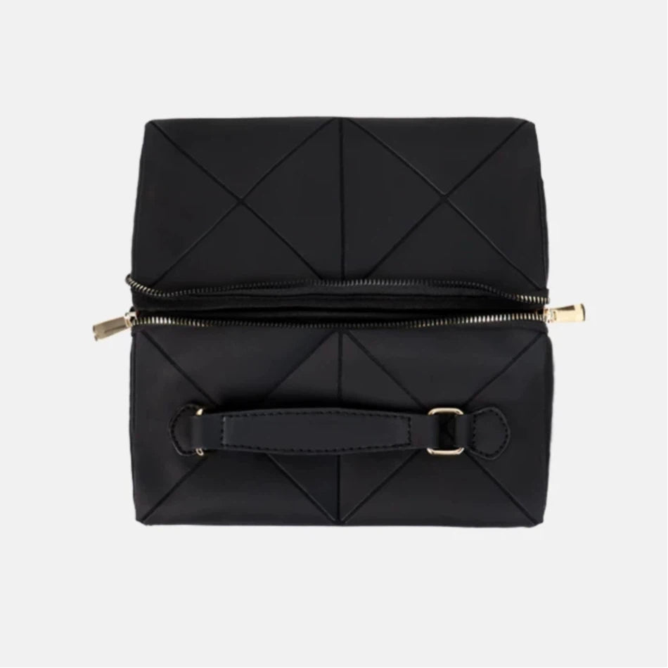 Folded black geometric-patterned makeup bag with gold zipper on a light gray background