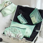 Green travel storage bags inside an open suitcase on a white surface