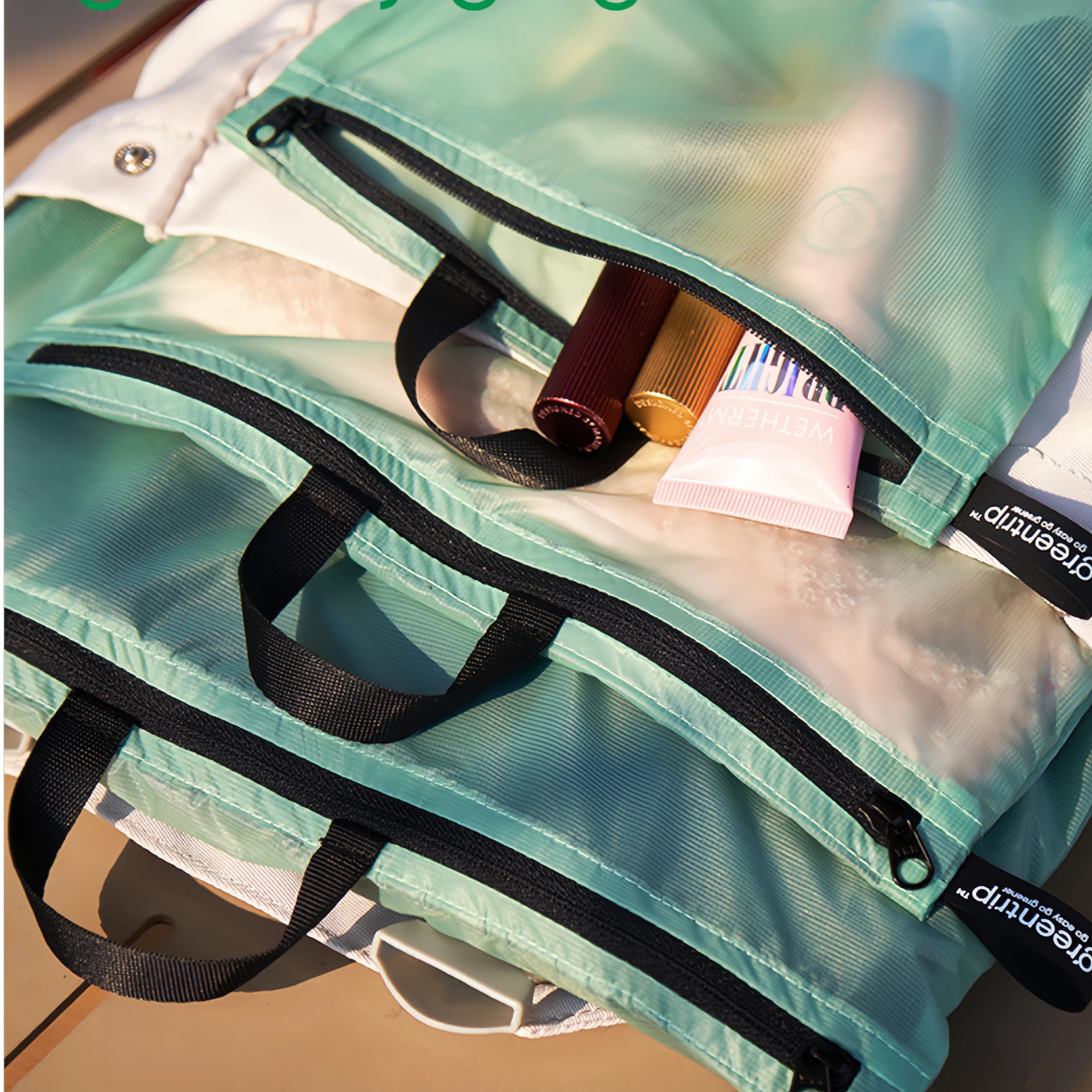 Green travel bags with black straps on a wooden surface.