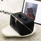 Black geometric makeup bag with gold zipper on a textured surface