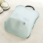 Light green travel bag on a textured surface with shoes in the background