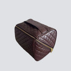 Quilted wine-coloured makeup bag with gold zipper on a light gray background