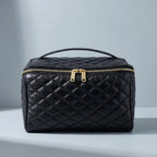 Black cosmetic bag with gold zipper on a gray background