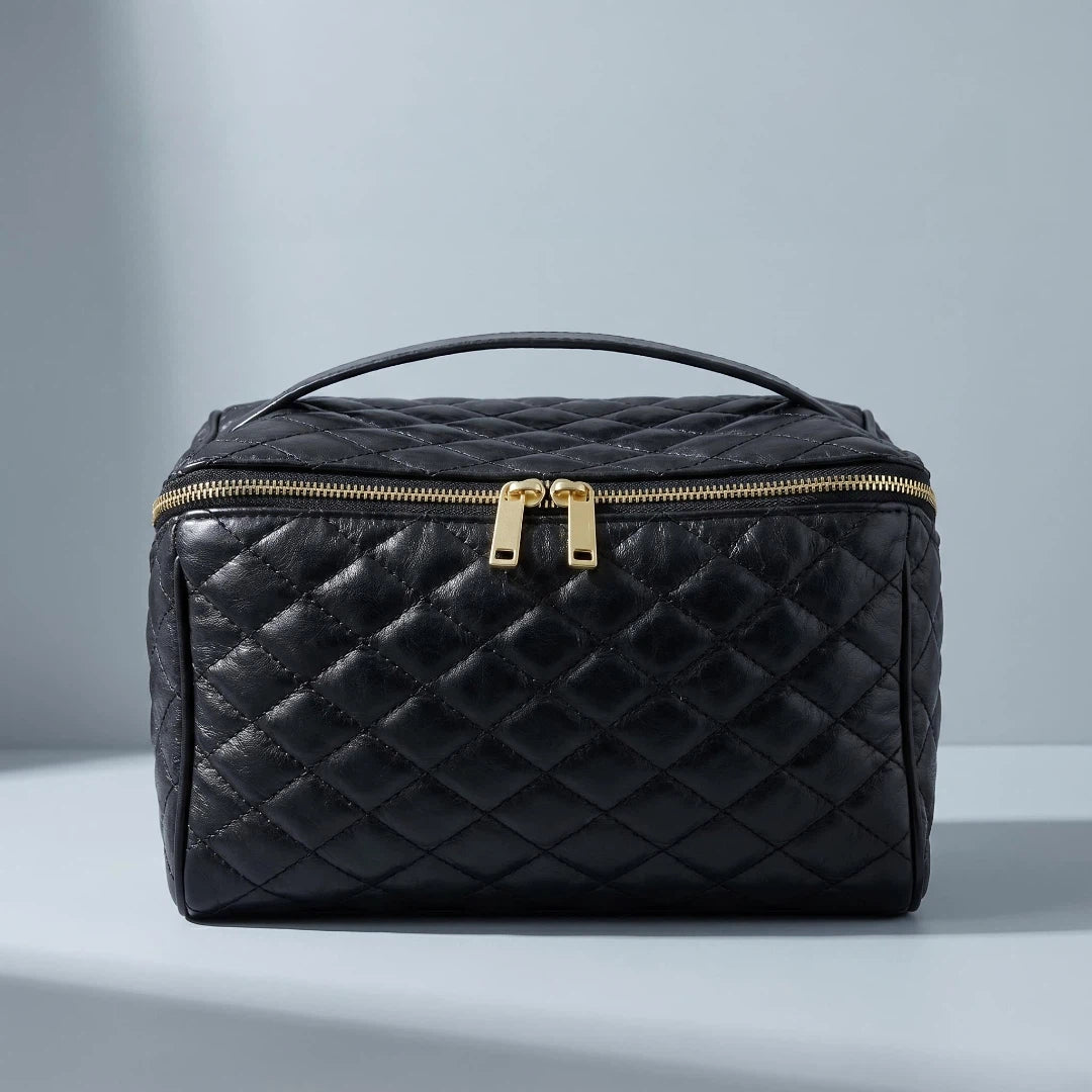 Black cosmetic bag with gold zipper on a gray background