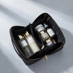 Black makeup bag with skincare products on a light gray background
