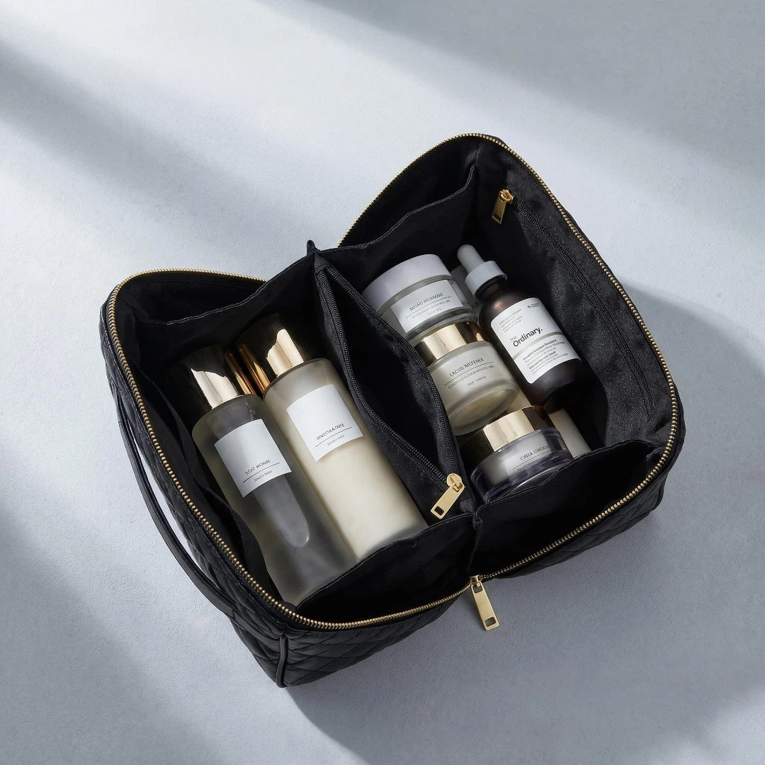 Black makeup bag with skincare products on a light gray background