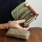 Person holding an open green jewellery bag with jewelry, sitting on a wooden surface.
