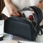 Black leather bag with a red item inside, held by hands on a white surface.