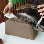 Olive grey leather bag with a person opening it on a white surface