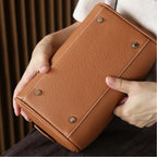 Brown leather bag held by a person with a blurred background