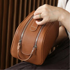 Brown leather bag held by a person with a blurred background