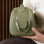 Green leather bag held by a person with a blurred background
