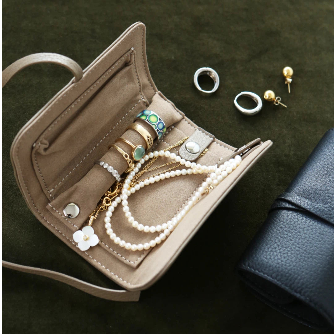 Jewelry organizer with necklaces, bracelets, and earrings on a dark green surface