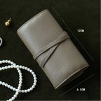 Olive grey leather jewelry roll with measurements on a dark surface