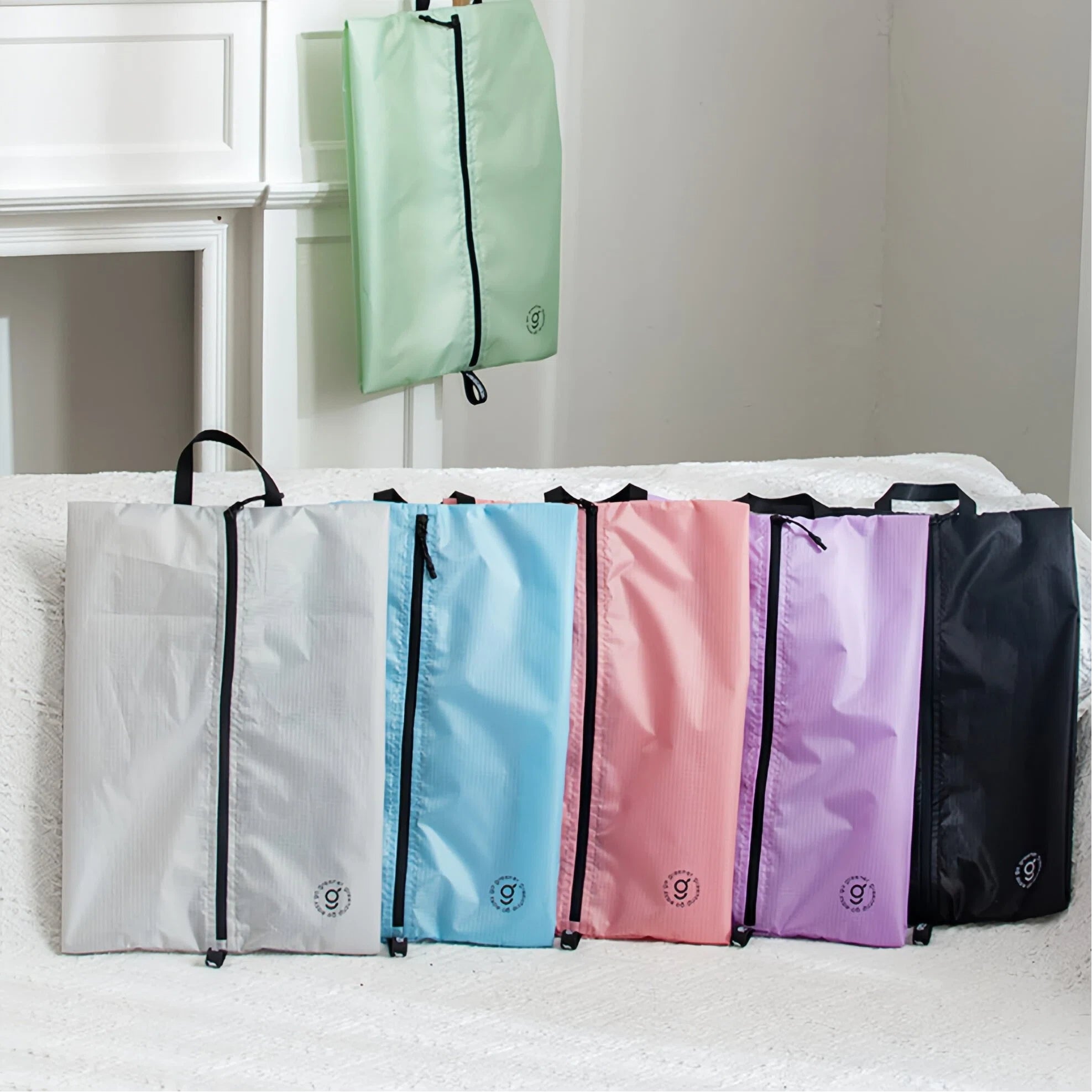 Six colorful bags (green, grey, blue, pink, purple, black) with a brand logo on a white surface.