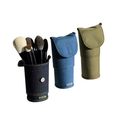 Set of makeup brushes in a denim holder with two additional holders in blue and green on a white background.