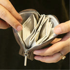 Person holding an open olive grey leather jewellery bag with multiple slots against a dark background