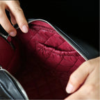 Close-up of a person opening a black quilted makeup bag.